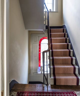 hallway with neutral walls and staircase with red stair runner