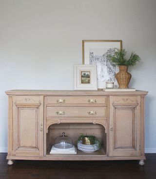 Refinished wooden buffet in hallway with a vase of flowers and frame