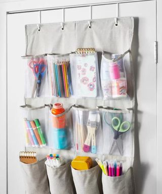 An image of an overdoor organizer on a white door with each pocket filled with craft supplies