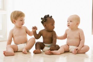 Three naked babies sit next to each other.