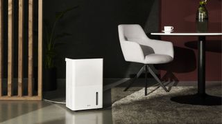 A modern home office with a swivel chair and a white dehumidifier plugged into the wall
