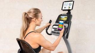 NordicTrack Commercial VR25 Recumbent review: a woman syncs her smartphone with the bike to share data from her recent workout