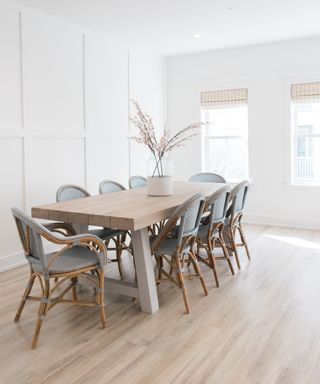Pared-back white dining room with wooden flooring and trestle style dining table