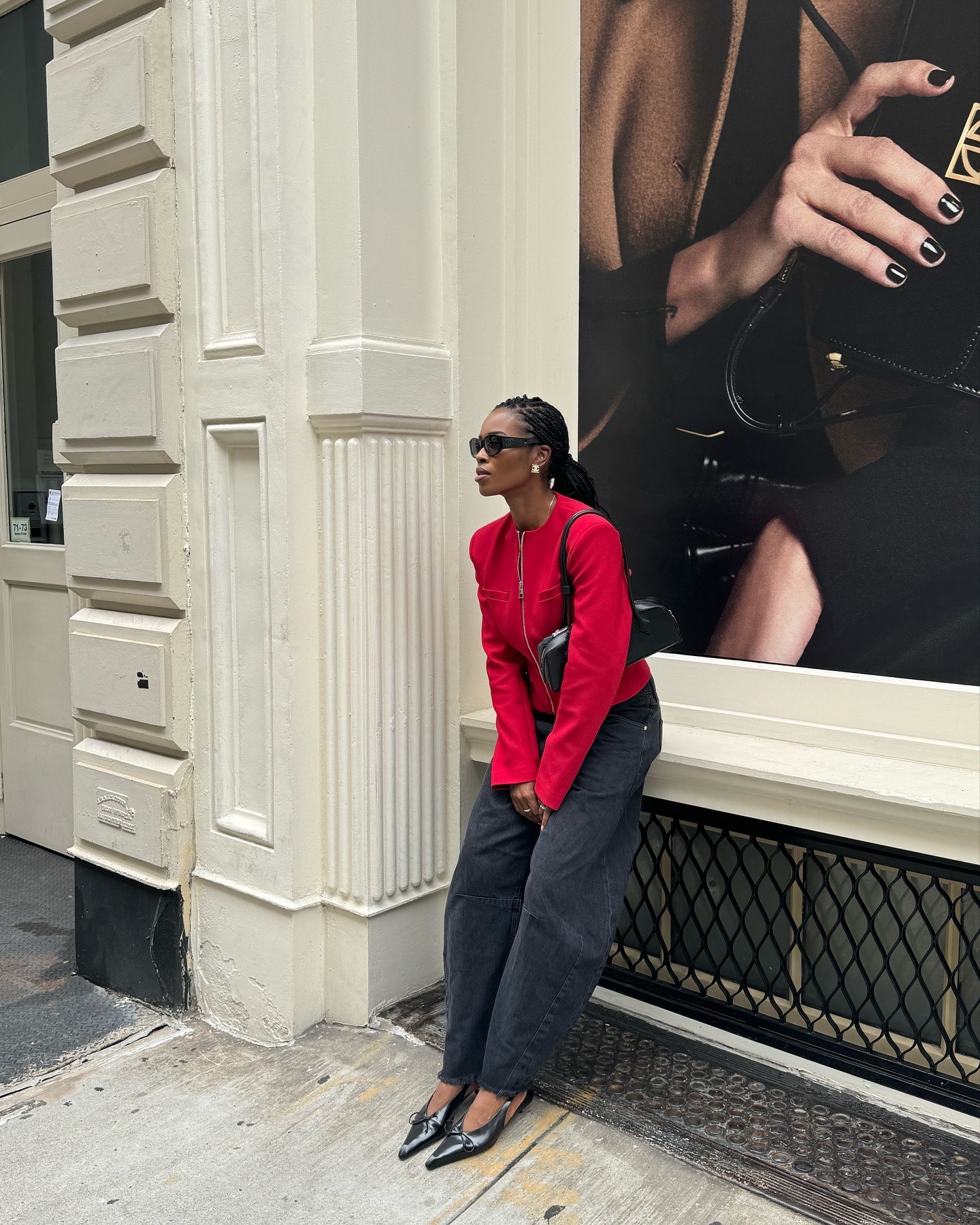 Woman wears red jacket, black barrel-leg jeans and black point toe heels