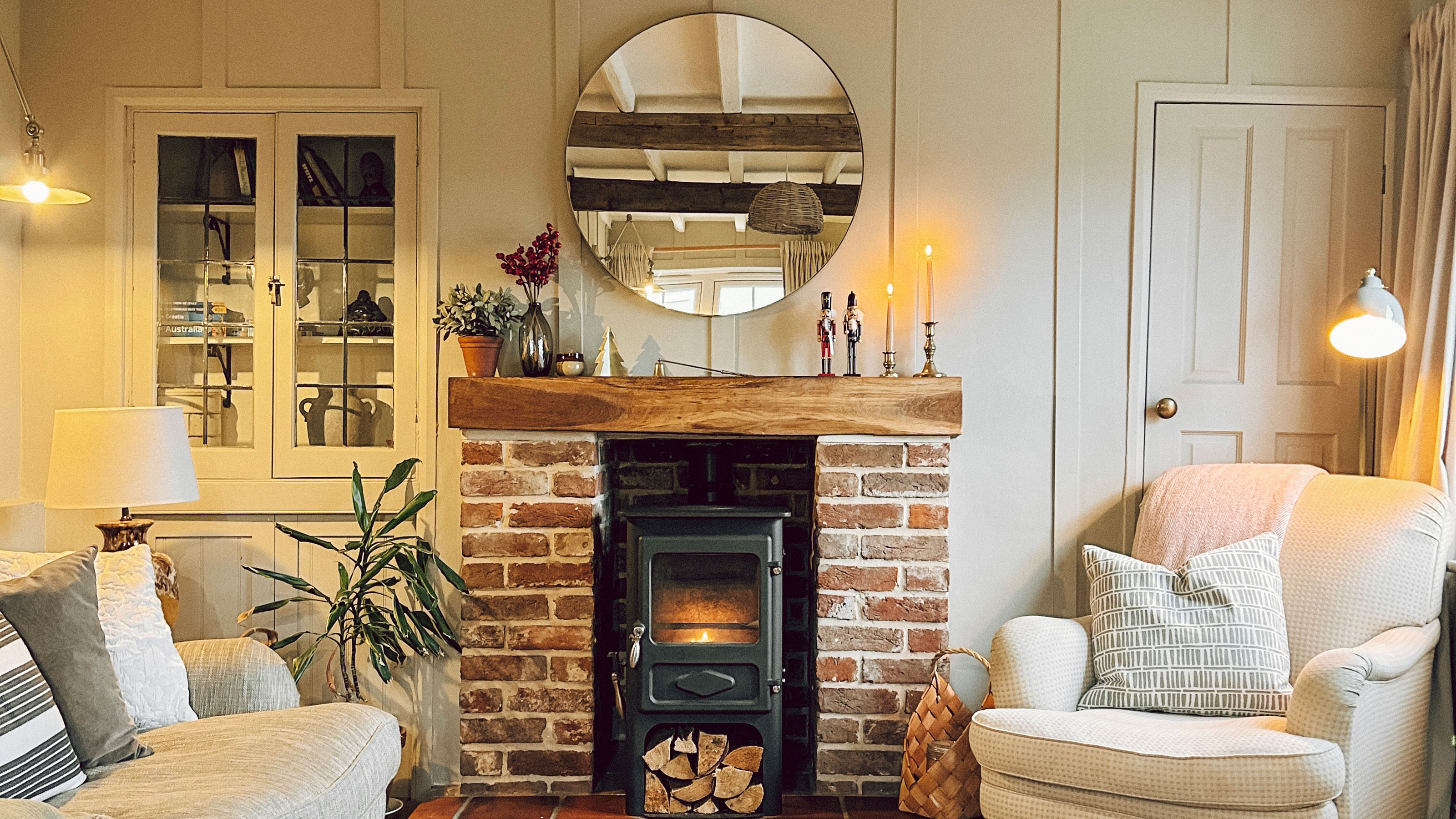 Living room with round mirror above brick-sided fireplace 