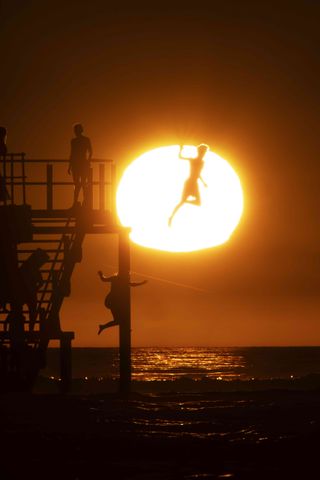 Veuve Clicquot Magnum Photos Emotions of the Sun: people silhouetted, jumping into sea