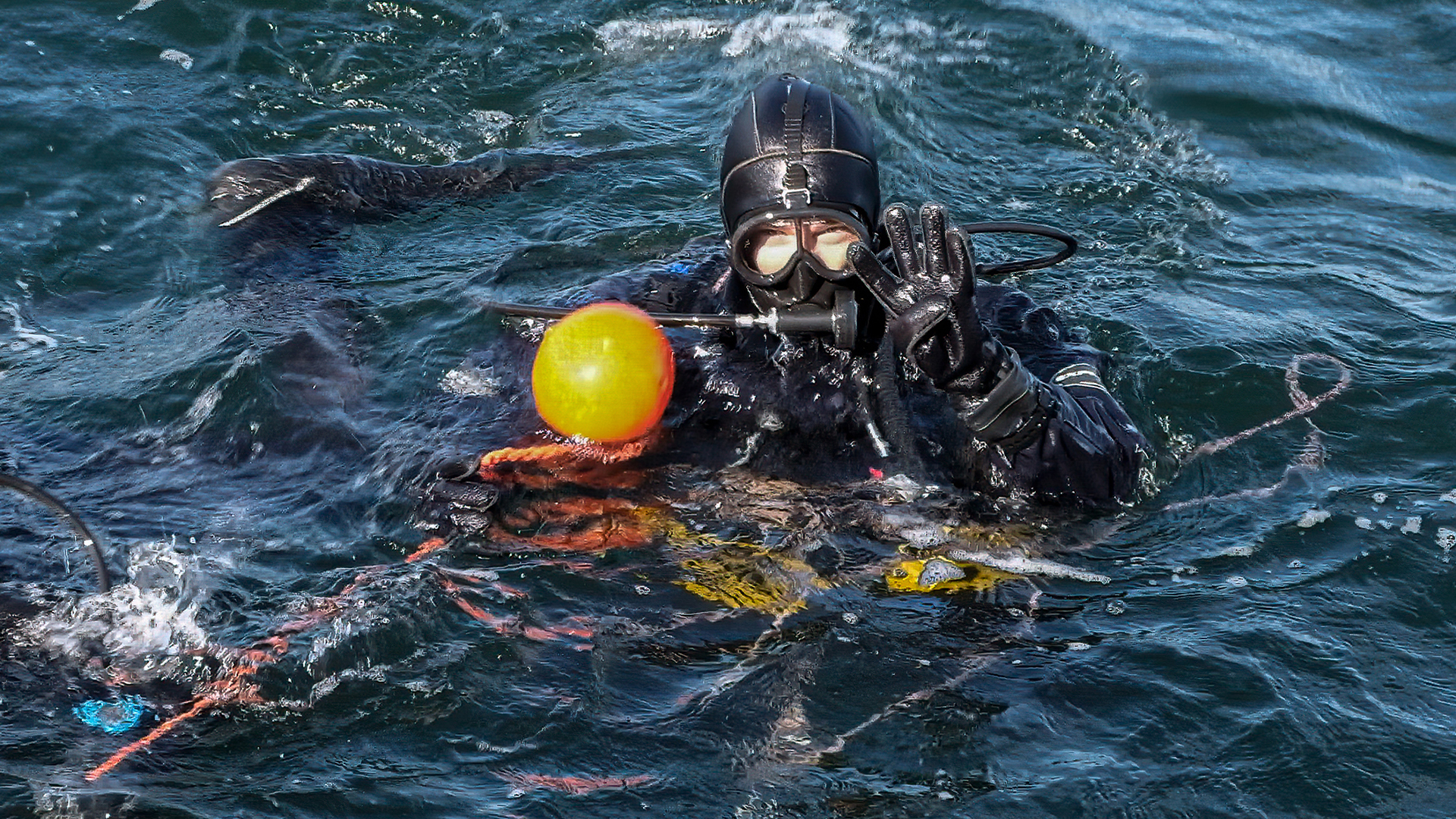 A researcher in scuba dive gear at the water surface before descent.