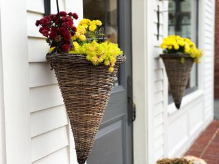 Two wicker cone planters flanking a door with mums in