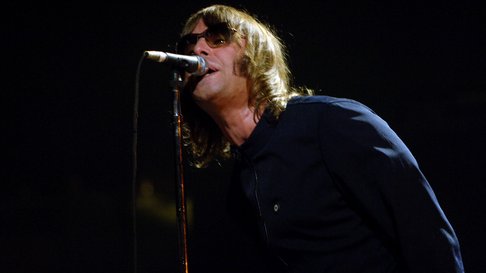 Liam Gallagher singing into a microphone 