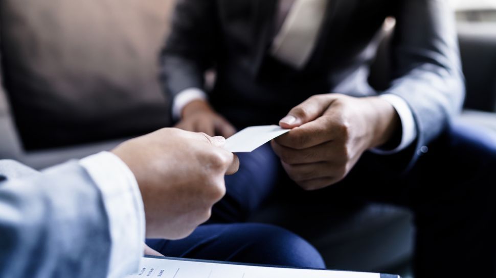 two hands passing a business card to each other