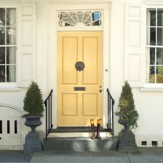 Yellow front door on white house with steps