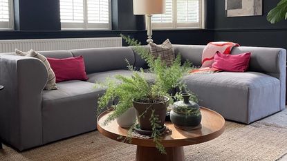 Corner of a grey sofa with assorted scatter cushions and a red Arket throw