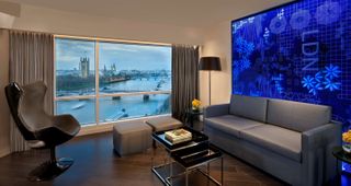 The lounge area of a hotel room at Riverbank Radisson Hotel in London. The city and the River Thames can be seen through the window.