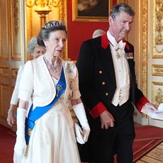 Princess Anne wearing a white gown and tiara walking with her husband
