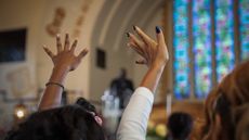 A stock photo of people praying at a church service. 