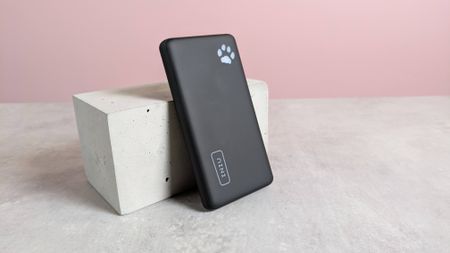 Iniu B41 power bank leaning on plinth on desk with pink background