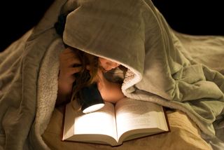 child reading in the dark with flashlight