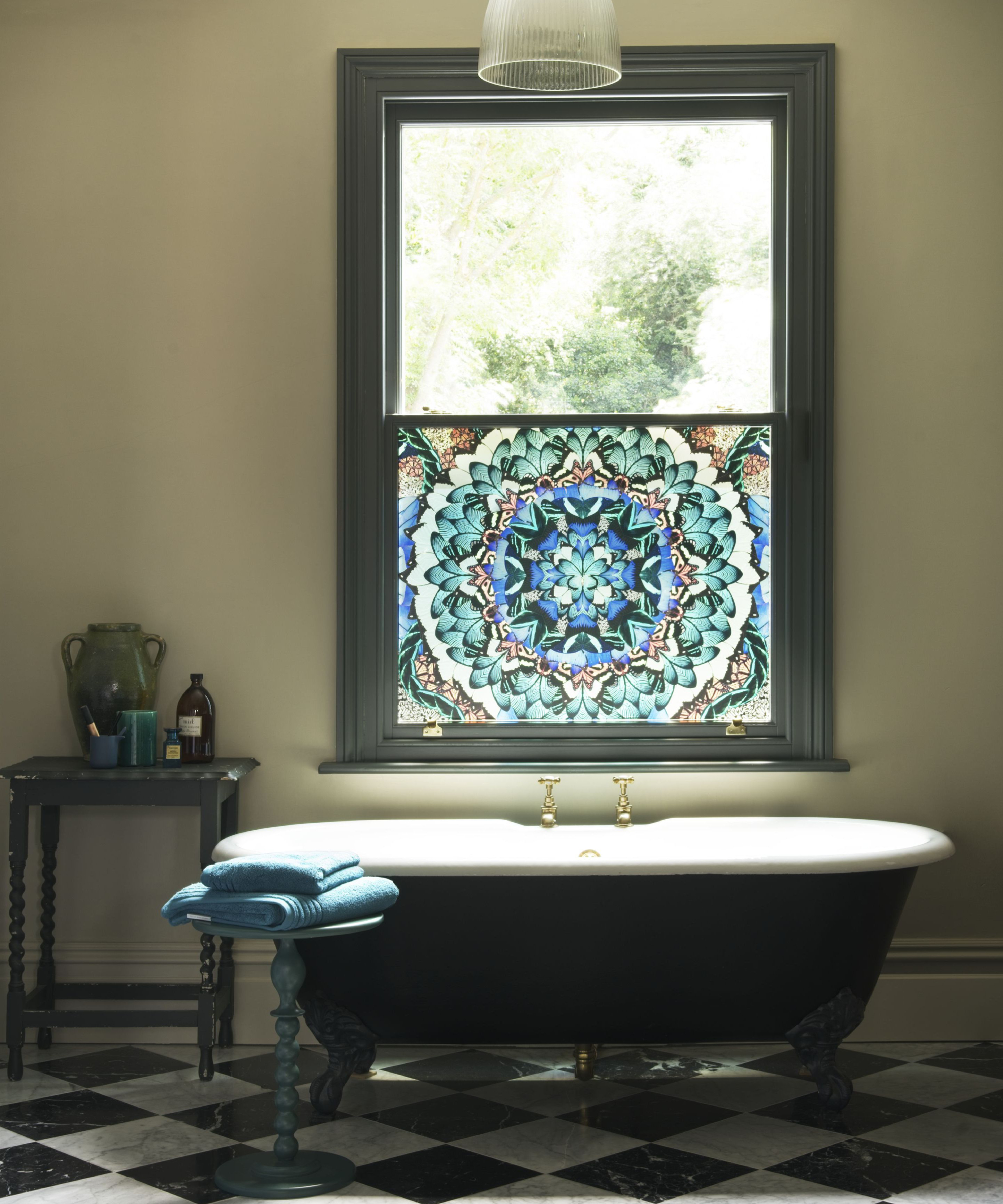 stained glass style window film on half of window above green sided freestanding bath