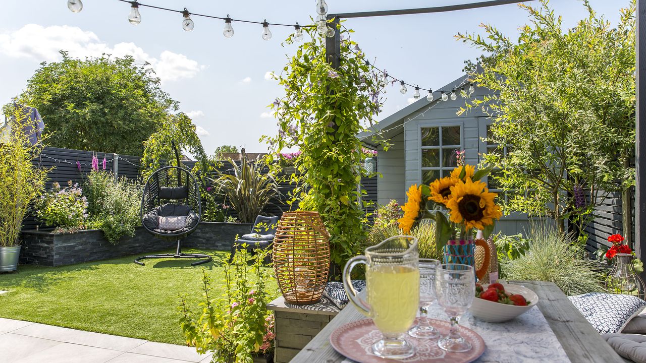 A view of a small rectangular garden makeover with a pergola seating area, shed and lawn with egg chair in the background