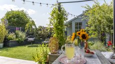 A view of a small rectangular garden makeover with a pergola seating area, shed and lawn with egg chair in the background