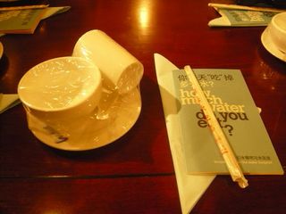 Sterile, plastic-wrapped plates and cups alongside a pair of paper-wrapped chopsticks. There is also a leaflet titled "How much water do you eat?"