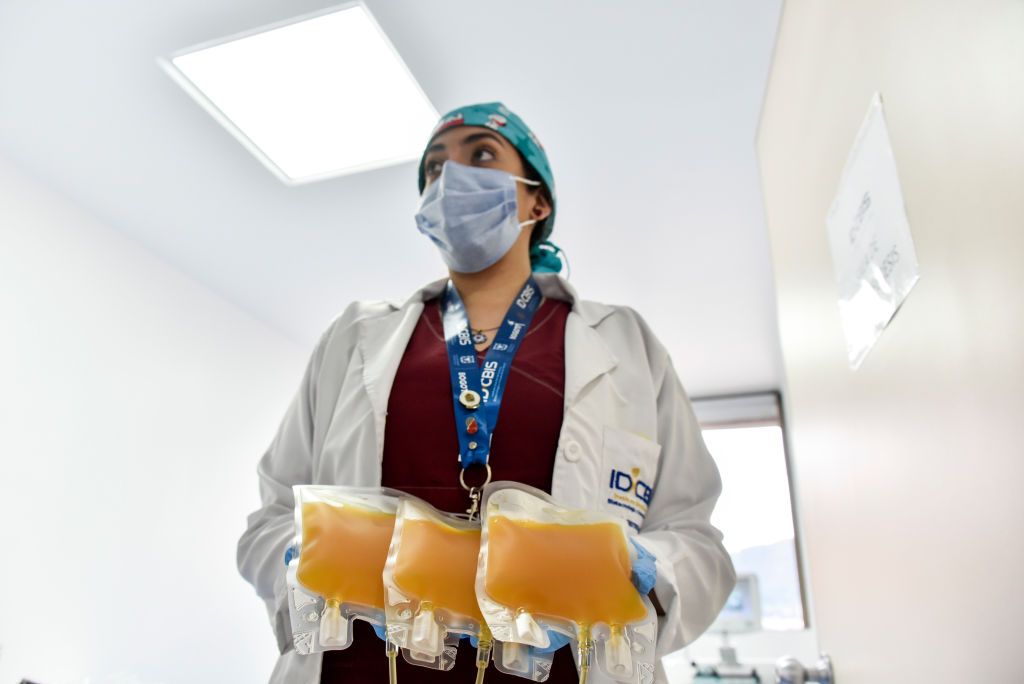 A nurse carries bags of plasma.