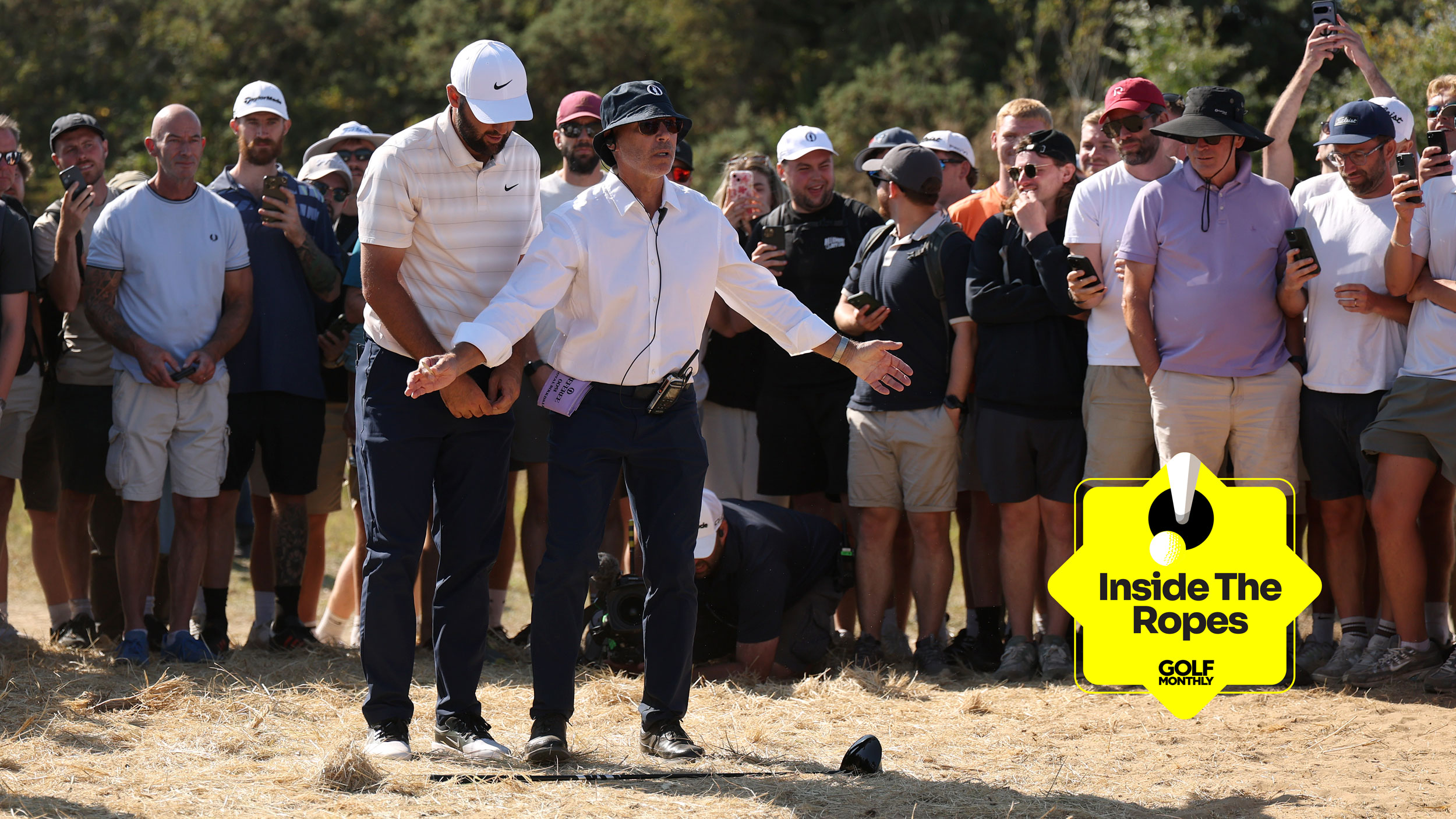 Scottie Scheffler stands behind an R&amp;A rules official during round four of The Open in 2026