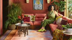 Justina Blakeney on a red couch with a patterned rug on the floor