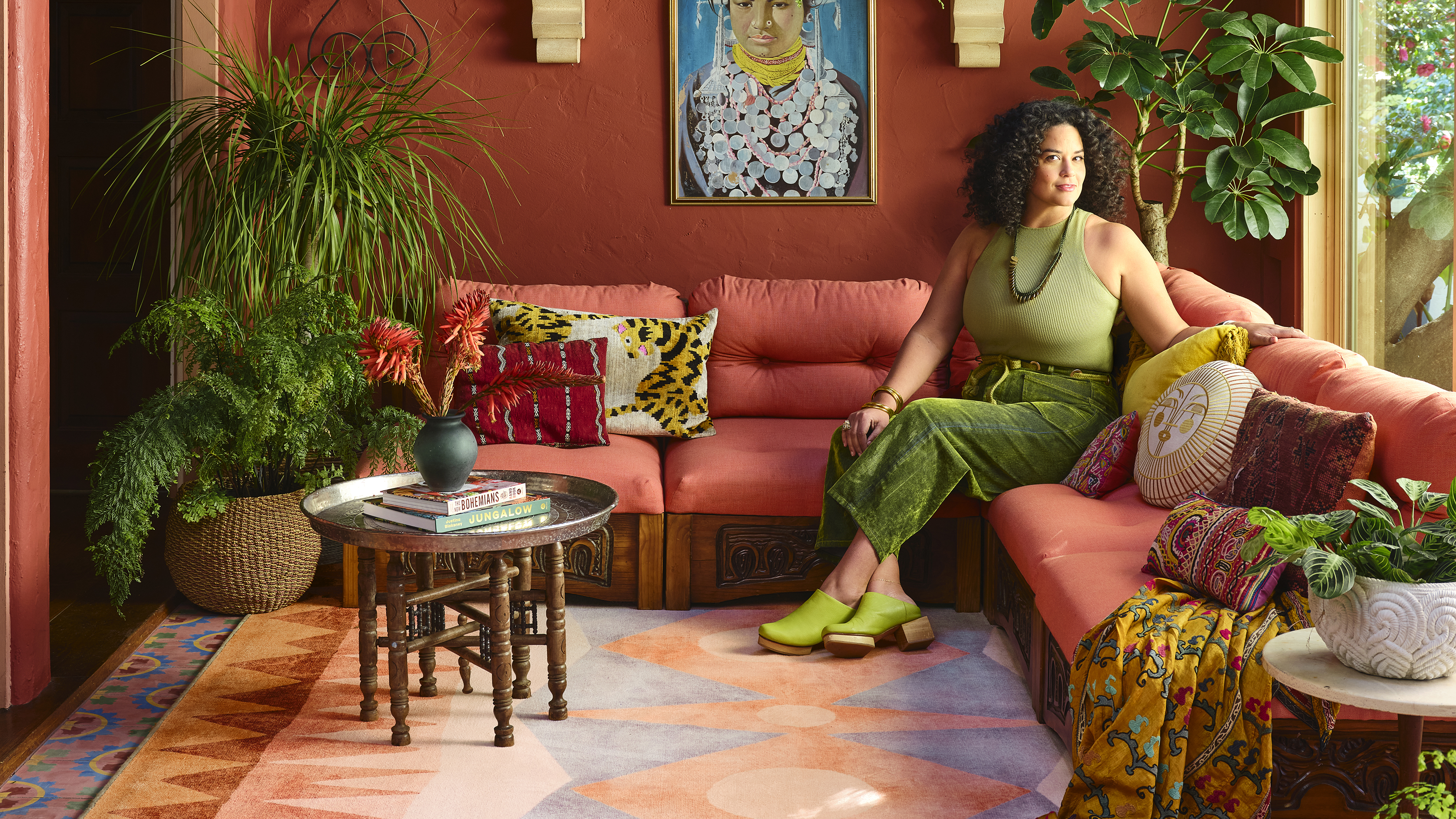 Justina Blakeney on a red couch with a patterned rug on the floor