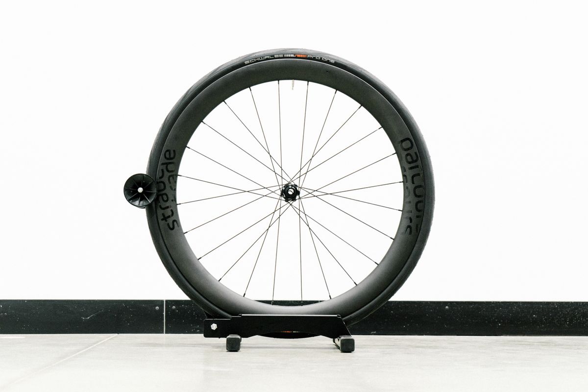An aero road wheel stands against a white wall