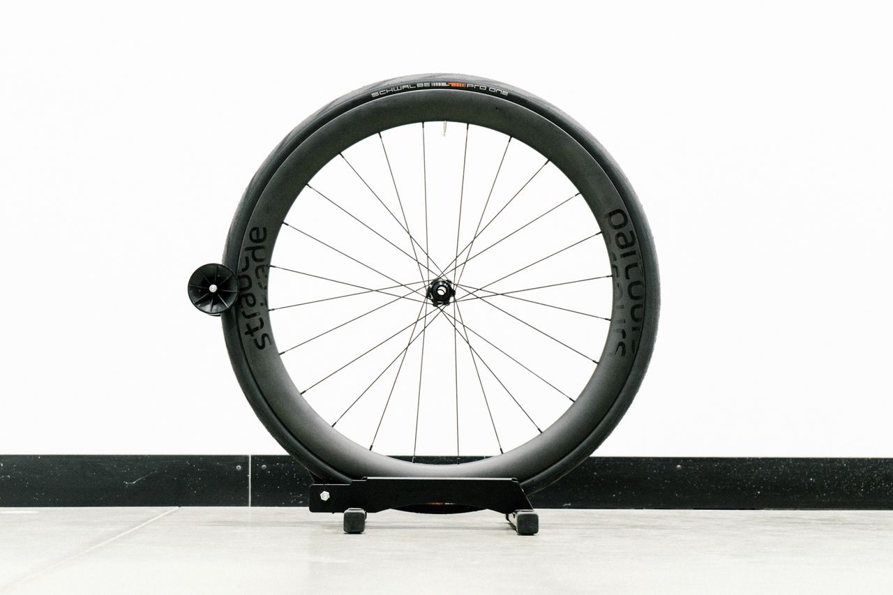 An aero road wheel stands against a white wall