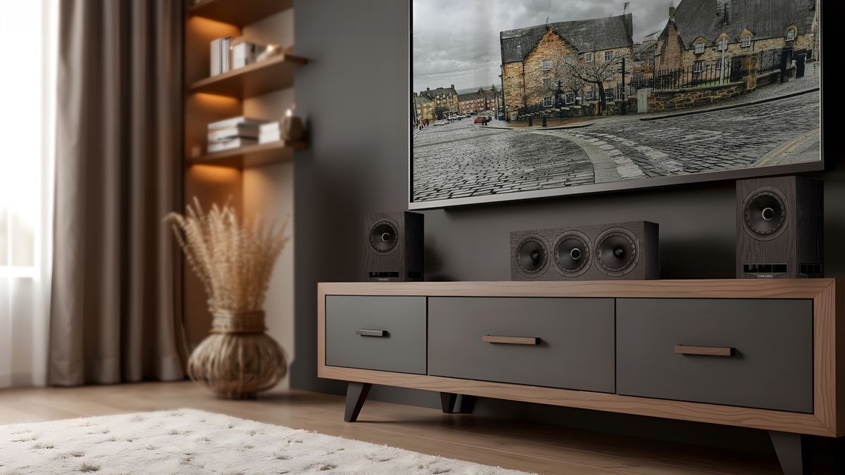 Fyne Audio F550E Series speakers on a TV cabinet beneath a wall-mounted TV in a lounge.