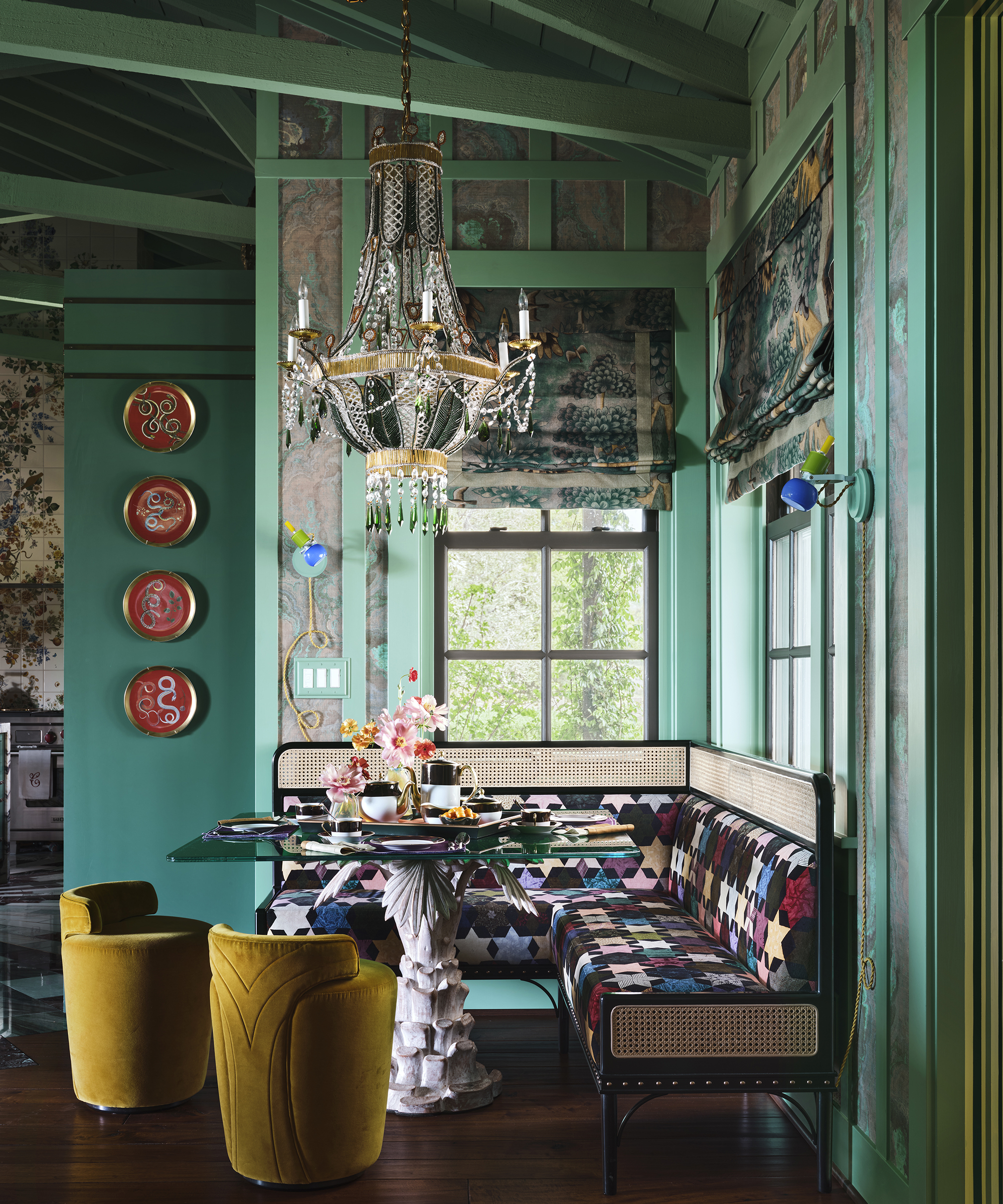 breakfast nook with built in banquette and green walls and a big chandelier over the table