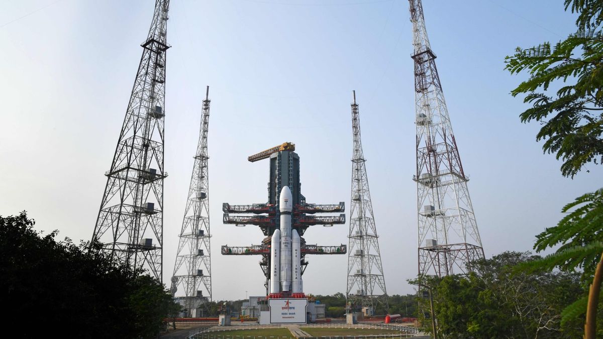 A white rocket stands on the launch pad under a cloudy sky