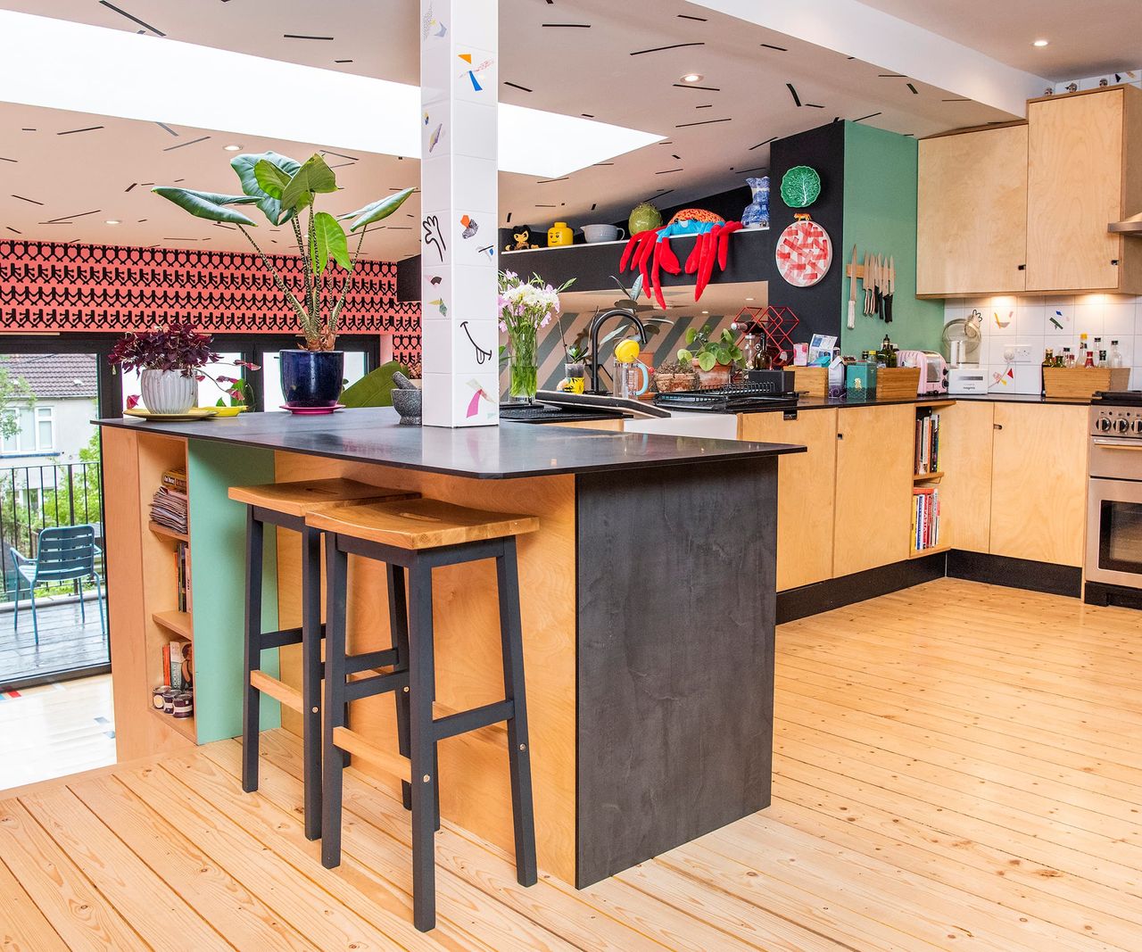 A wooden floor kitchen with a U-shaped kitchen island and playful walls with childlike designs like smiley faces and stripes