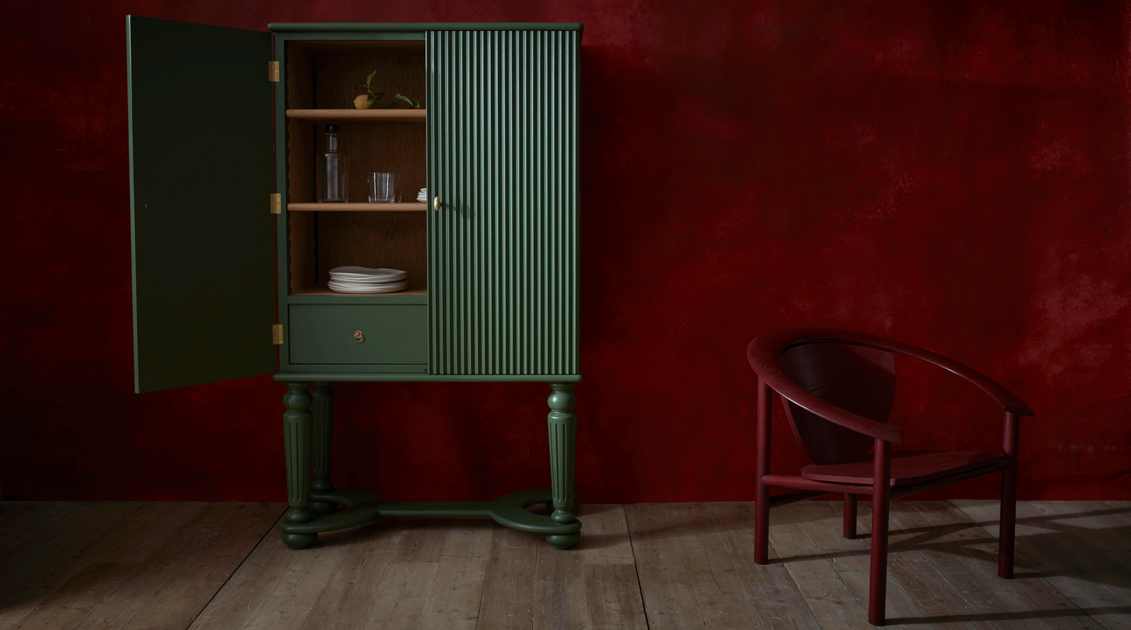 Dark green cabinet and red chair against a red wall