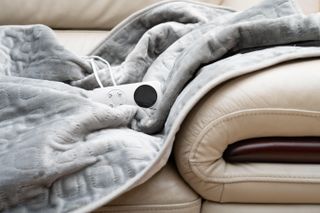 Electric blanket and controller draped on a cream sofa