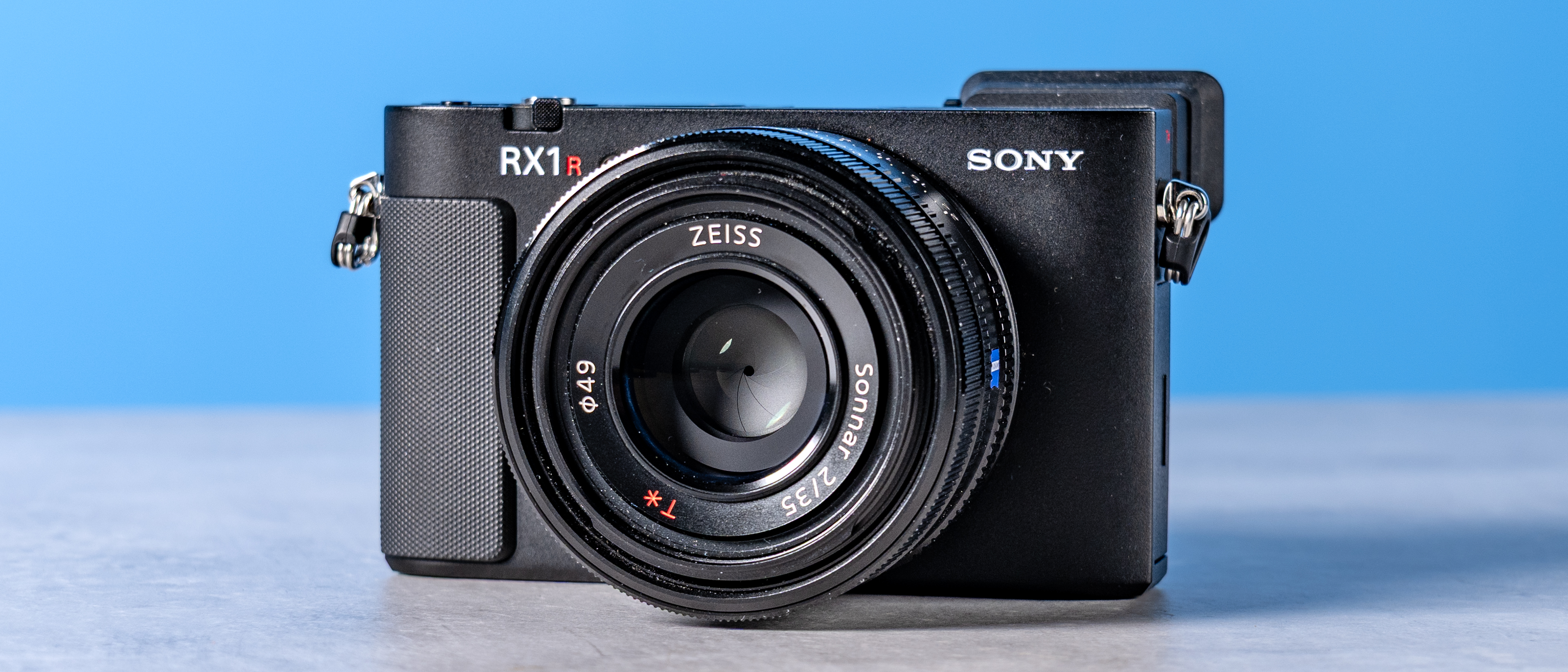 A photo of the Sony RX1R III on a stone surface with a blue background