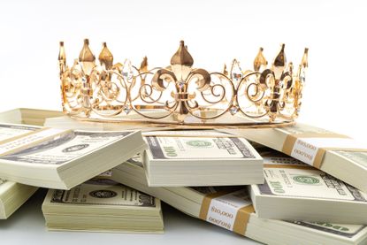Cash is king, economic treasure and financial successful retirement conceptual idea with gold metal crown on pile of 100 dollar bills isolated on white background