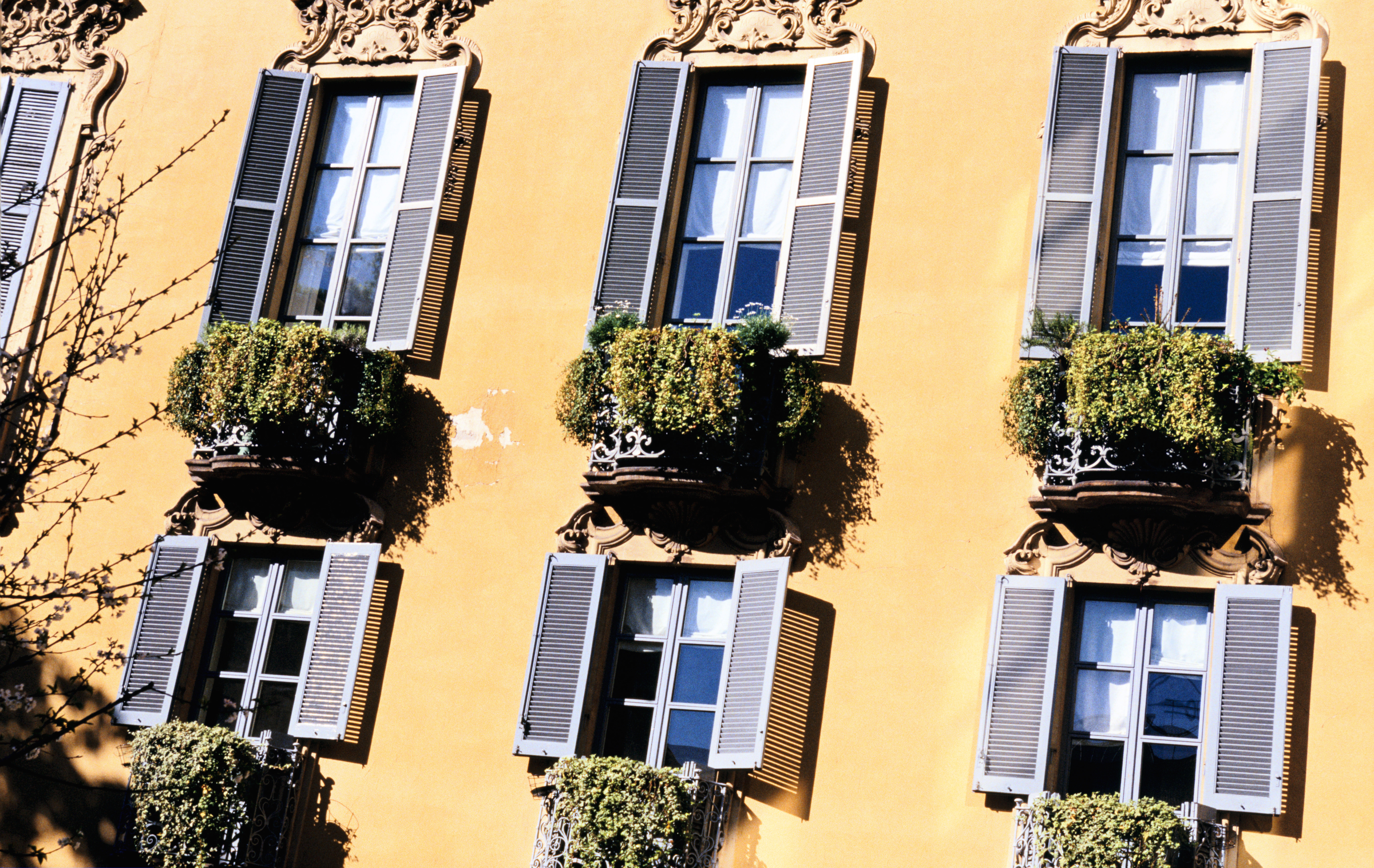 section of MIlanese apartment facade with windows and open shutters
