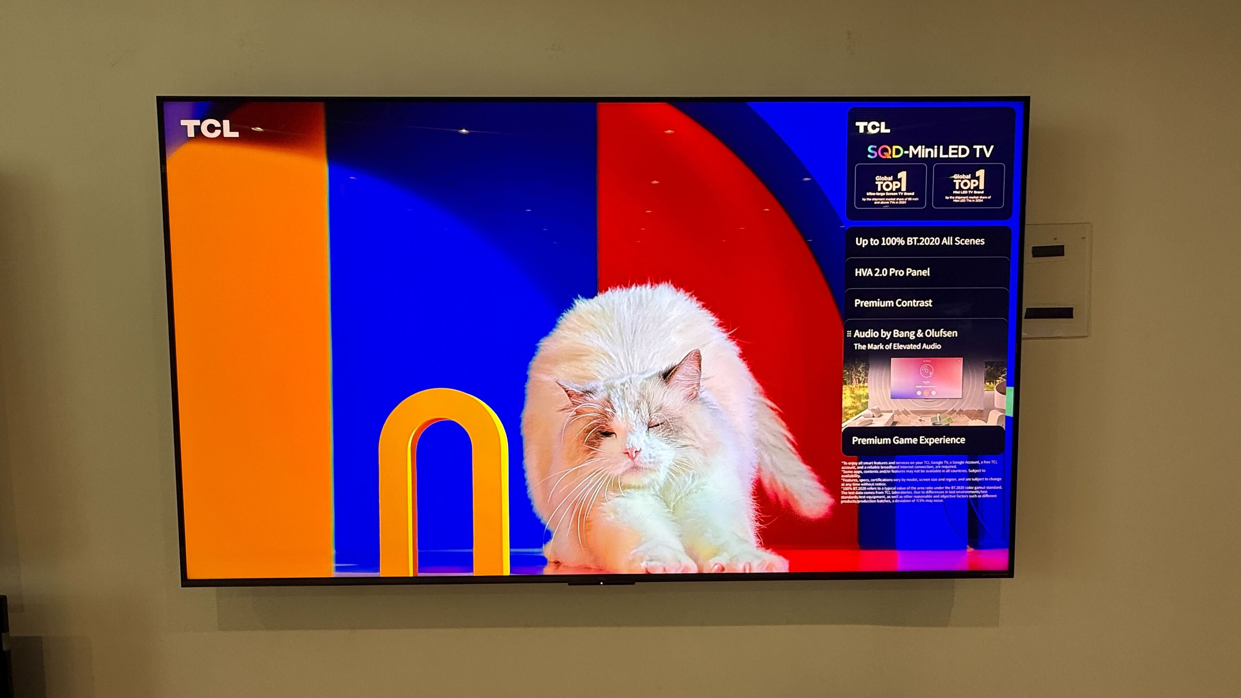 Wall-mounted TCL C7L with vibrant demo content on screen