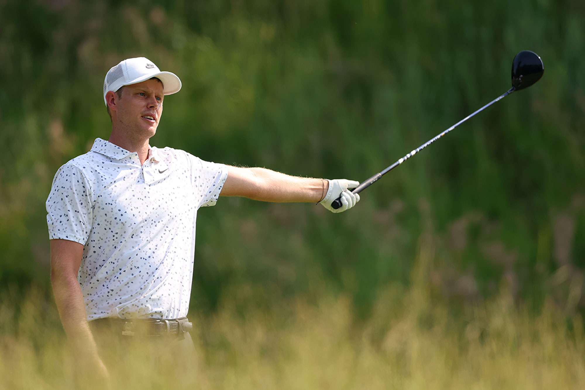 Cam Davis indicating with a driver in his outstretched arm that his golf shot has gone off line, with a despondent look on his face
