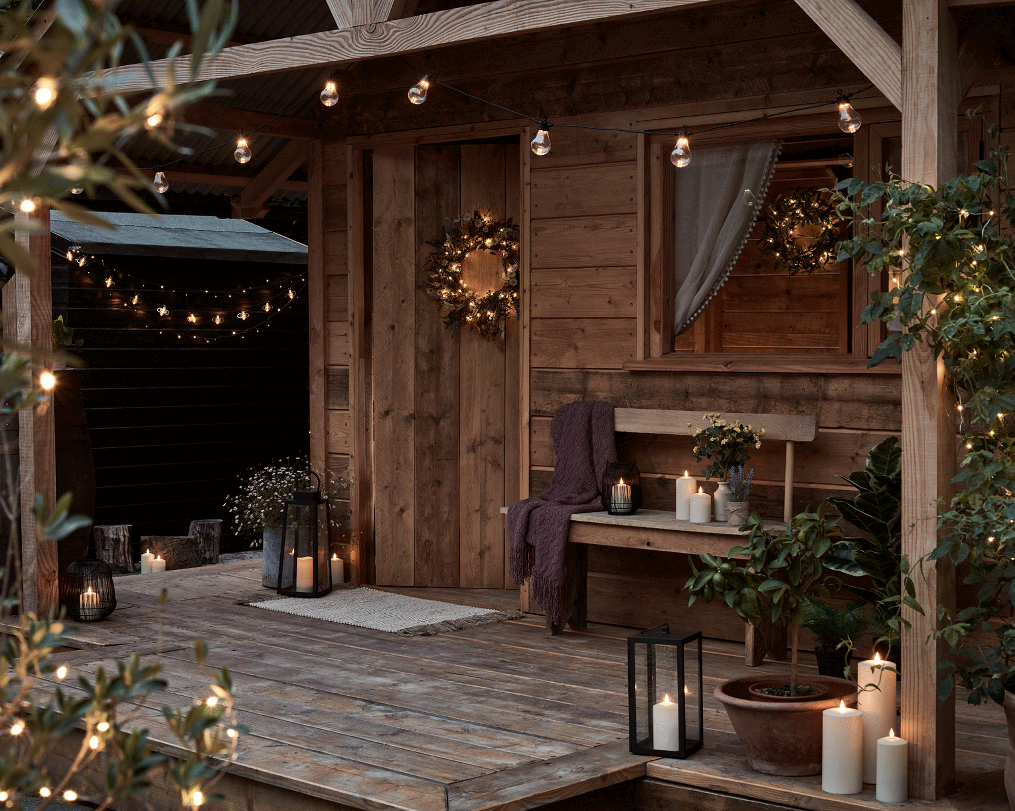Ambient porch setting with candles and festoon lights.