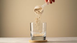 Woman's hands pouring protein powder into a glass