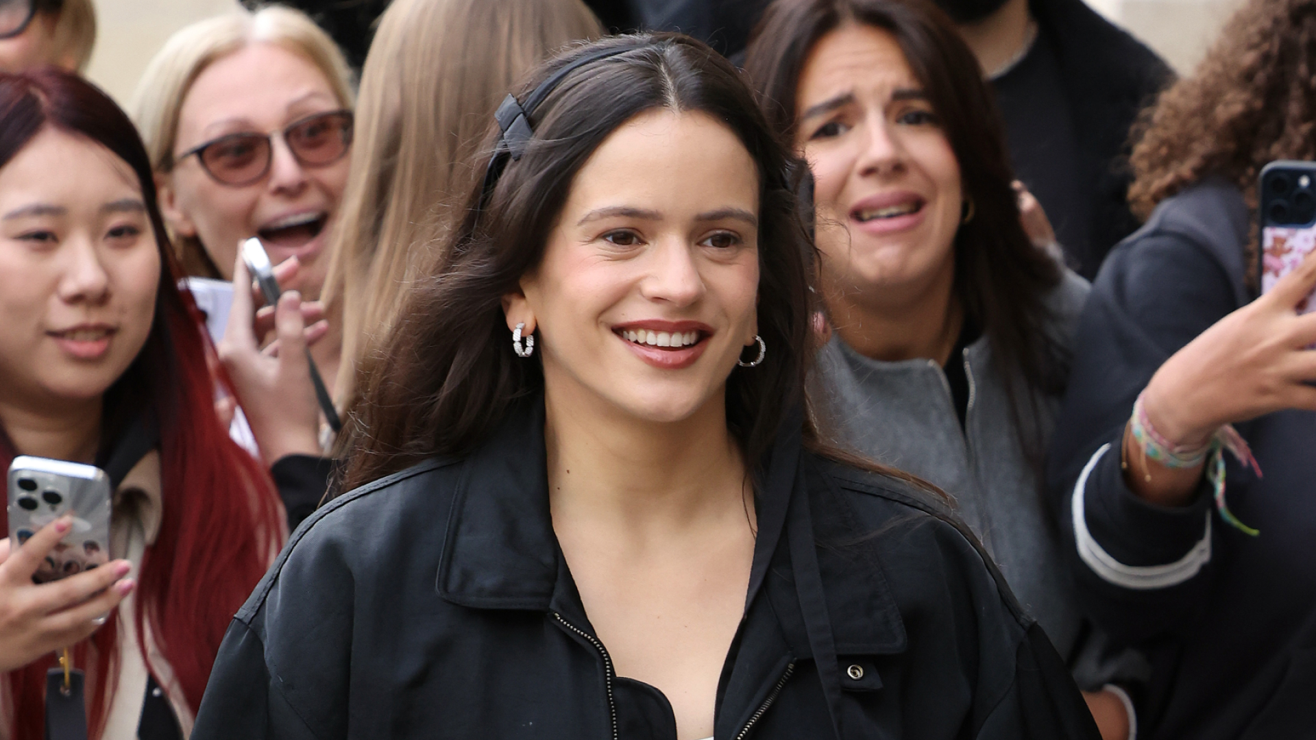 Rosalia wears a black jacket and is surrounded by fans