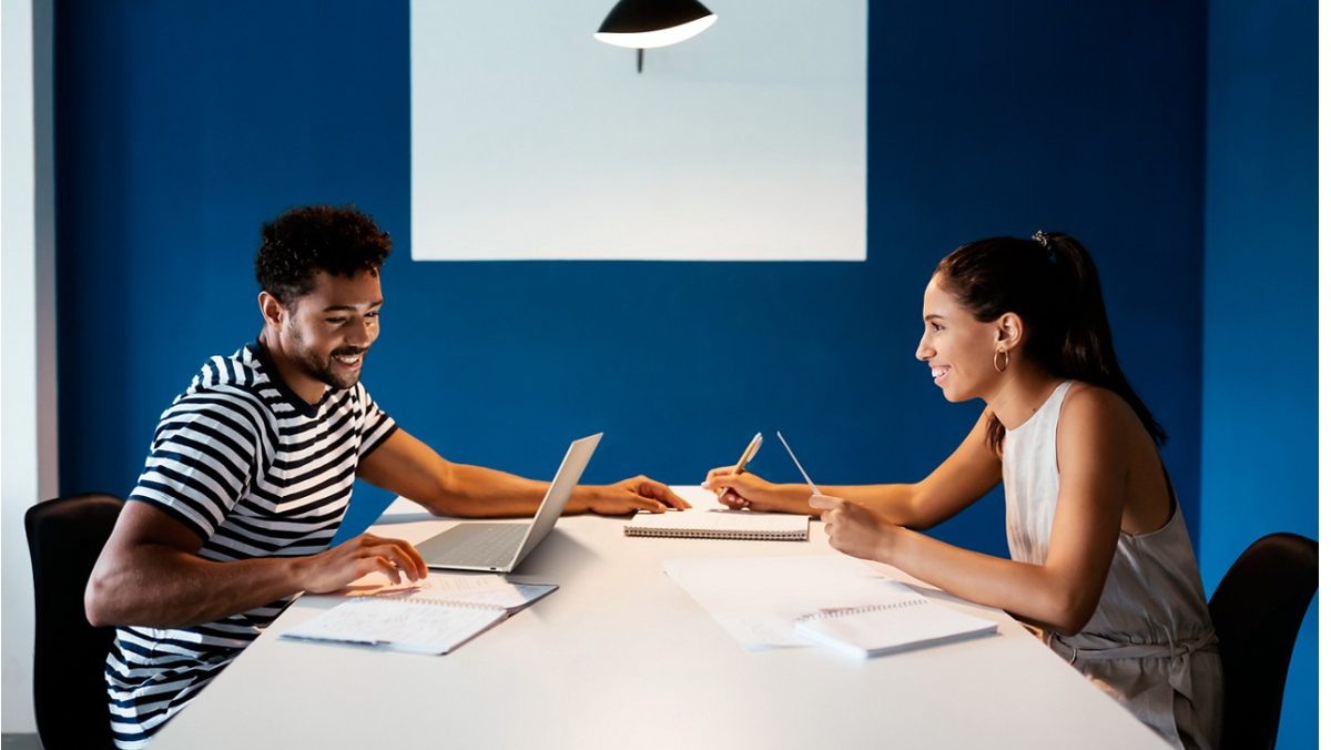 Two people sat at a table using Dell laptops