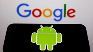 The Android logo shows on a black phone screen, while the Google logo is displayed on a wall in the background