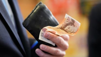 Jeremy Hunt holds a £10 note on a visit to Accrington Market Hall, on 19 January, 2023