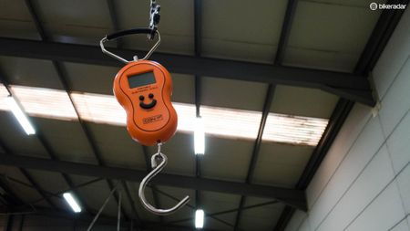 A weighing scale hangs from the high ceiling by an old bike chain – essential equipment to make sure the bikes are UCI compliant