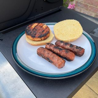 Sausage and burger on the side of a BBQ